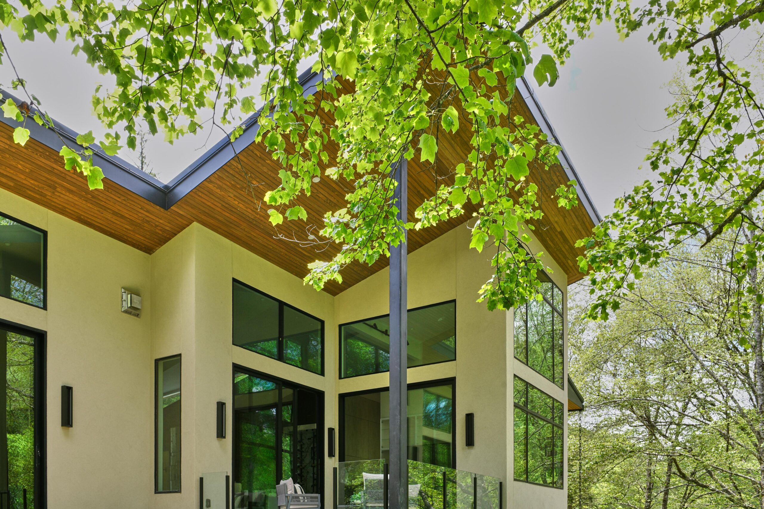 a_house_with_a_patio_and_a_large_tree_brdb_highlands_nc_porch_natural_light
